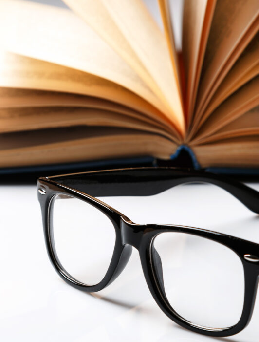 Open book and reading glasses resting on a desk