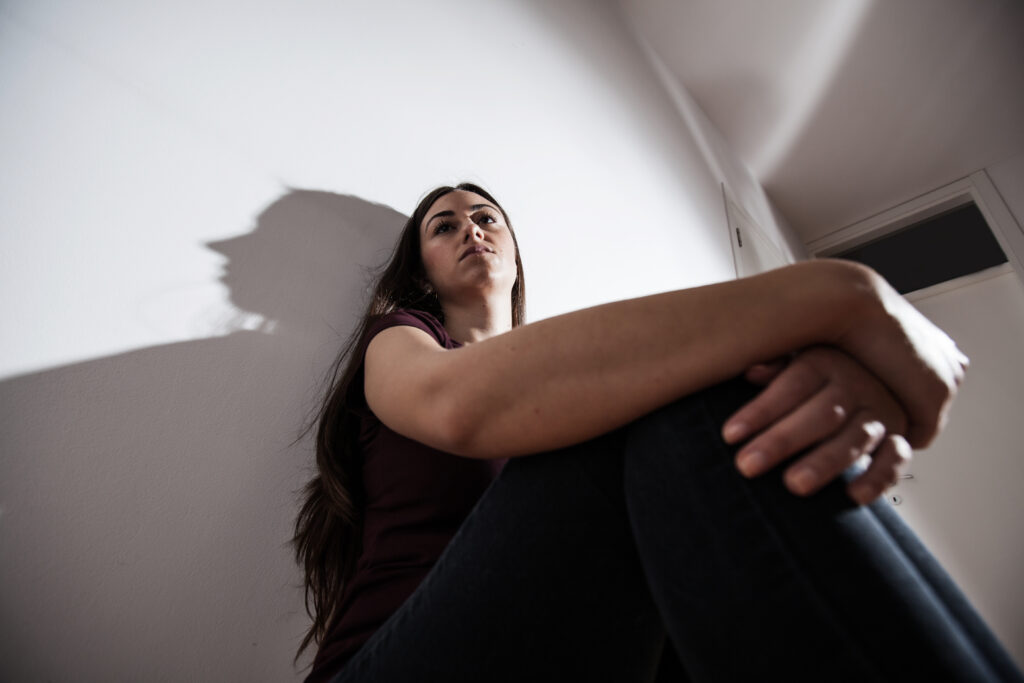Woman resting her head on her knees while sitting alone