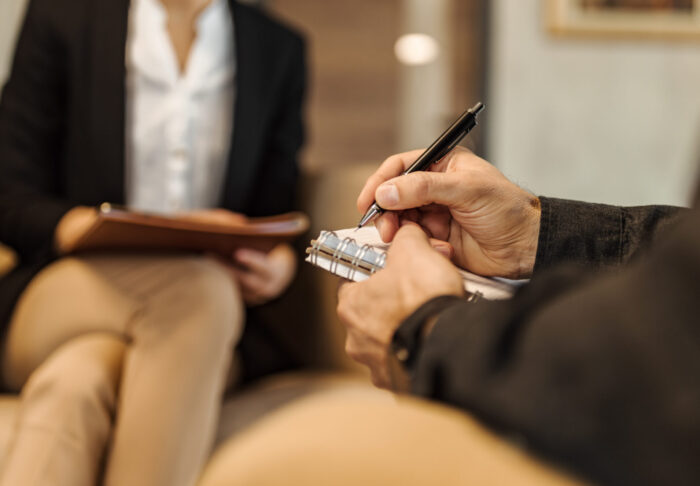 Two colleagues collaborating and sharing notes at a desk